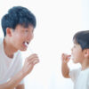 子供の歯磨き習慣を教える父親と楽しそうに磨く男の子のイメージ